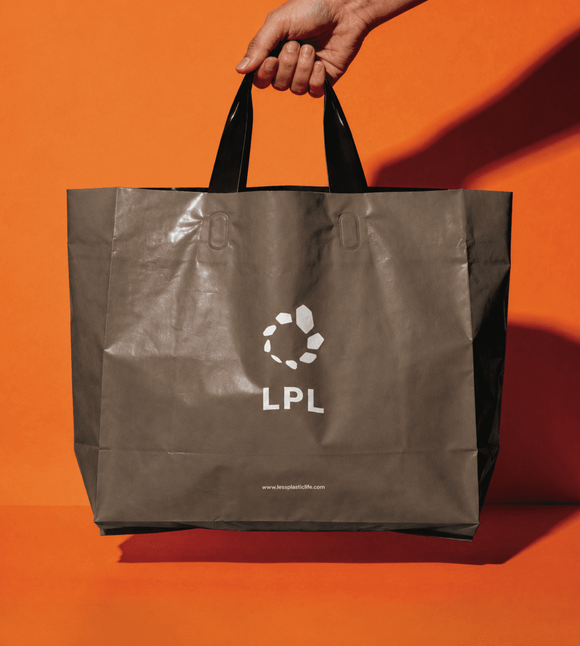 주황색 배경에서 손으로 들고 있는 LPL 에코백